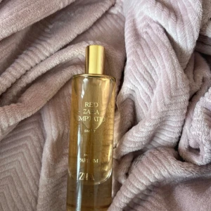 Zara Red Temptation Sweet Parfym - Zara Red Temptation Sweet Eau de Parfum i en elegant, genomskinlig glasflaska med guldfärgat lock. Doften är modern och trendig, perfekt för dig som gillar söta och fräscha toner. Flaskan har en stilren design och känns lyxig att ha framme.