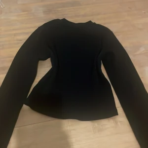 Svart långärmad tröja Gina Tricot - En svart långärmad tröja från Gina Tricot i storlek S. Tröjan har en enkel och stilren design med rund hals och figurnära passform. Perfekt att matcha med jeans eller kjol för en clean look.