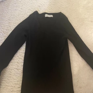 Svart v-ringad tröja från Primark - Säljer en svart v-ringad tröja  från Primark i storlek 2XS. Tröjan har lång ärm och v-ringad hals, vilket ger en clean och stilren look. Materialet är mjukt och stretchigt, perfekt för dig som gillar bekväma och enkla outfits.