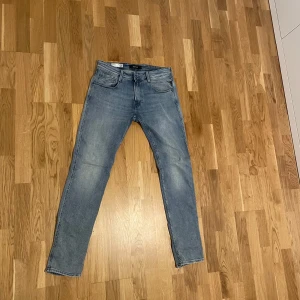 Replay ljusblå slim jeans - Säljer ett par ljusblå jeans från Replay med klassisk femficksdesign och snyggt slitna detaljer. Jeansen har en slim passform och raka ben, tillverkade i mjukt jeansmaterial som sitter skönt hela dagen. Perfekta till sneakers och hoodie.