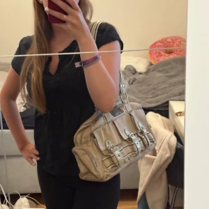 Handväska  - Axelväska som har mycket utrymme med två stora fack och mindre fack i dom. Dessutom finns förvaring utanpå väskan, köpt second hand. Y2K stil. 