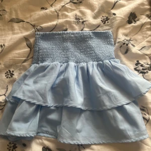 Ljusblå volangkjol från Gina Tricot - Supersöt ljusblå kortkjol från Gina Tricot med smockad midja och dubbla volanger. Kjolen har en luftig och flowy känsla, perfekt för dig som gillar en feminin och trendig stil. Passar dig som vill ha något som sticker ut och känns extra somrigt. Jag säljer den för 100kr med 30-50kr frakt, köp inte på ”KÖP NU”. betalningen sker i chatten med Swish 