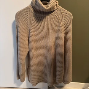 Beige ribbad polotröja ginatricot  - Snygg beige polotröja med ribbat mönster och hög krage. Perfekt för lager-på-lager och chill höst- eller vinterstil.