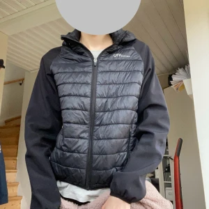Svart quiltad jacka - Svart jacka från OTP Sportwear med quiltad framsida och huva. Jackan har släta svarta ärmar, dragkedja framtill och två fickor med dragkedja. Perfekt för kyliga dagar och har en sportig vibe!😻Varm och skön med avtagbar luva. Storlek 170, men passar också XS🩷I använt skick så finns små defekter! 