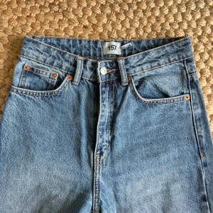 Blå jeans - Klassiska blå jeans från Lager157 i rak modell med fem fickor och hög midja. Jeansen har mellanljus tvätt, kontrastsömmar och är tillverkade i bomullsdenim. Perfekta för en avslappnad och tidlös look. 💙 Önskar du veta exakta mått? Tveka inte att höra av dig!
