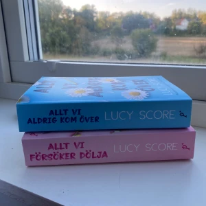 Allt vi aldrig kom över / Allt vi försöker dölja - Två färgstarka böcker av Lucy Score med charmiga omslag och blommiga detaljer. Perfekta för dig som gillar romantiska berättelser och vill ha något lättsamt och engagerande att läsa. Passar unga vuxna som söker både känslor och humor.