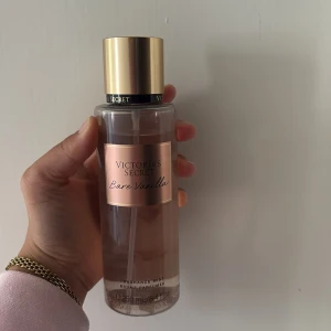 Victoria's Secret Bare Vanilla mist - Fräsch och söt body mist från Victoria's Secret i doften Bare Vanilla. Flaskan är transparent med guldig kork och etikett i roséguld. Innehåller 250 ml och har toner av vispad vanilj och mjuk kashmir. Perfekt för dig som älskar varma, krämiga dofter.