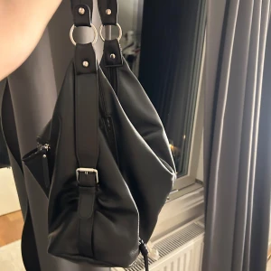 Svart handväska  - Svart handväska med silverdetajer. Rymmer mycket med många småfack. 