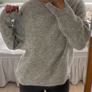 Grå stickad tröja från Carin Wester - Mysig stickad tröja från Carin Wester. Tröjan har rund halsringning, lång ärm och en synlig söm mitt bak. Lite noppig då jag har använt den en del! 