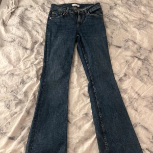 Blå bootcut jeans från Gina tricot  - Snygga blå jeans från Gina tricot i klassisk bootcut-modell. Jeansen har normal passform och är tillverkade i ett tåligt denimtyg. Perfekta för dig som gillar en tidlös look med lite utsvängda ben.