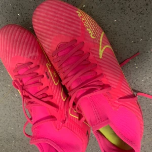 Nike Zoom rosa fotbollsskor - Säljer ett par Nike Zoom fotbollsskor i en riktigt skarp rosa färg med gula detaljer och snörning. Skorna har en randig design och platt sula med dobbar för grymt grepp på planen. Lätta och smidiga med syntetmaterial som ger bra känsla och kontroll. Hör av er vi minsta lilla !!!