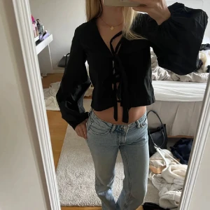 Svart croppad blus med knyt - Säljer en svart croppad blus med långa puffärmar och snygg knytning framtill. Toppen har v-ringning och ger en trendig look som passar perfekt till jeans eller kjol. Perfekt för dig som gillar stilrena och coola plagg. använd en gång💞💞