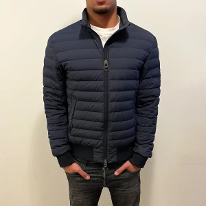 Colmar Originals dunjacka herr - Snygg dunjacka från Colmar Originals i mörkblått med quiltad design och hög krage. Jackan har dragkedja framtill, ribbade muddar och diskret logga på ärmen. NYPRIS:4495Kr. MITT PRIS: 1999Kr.