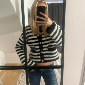 Randig kofta med guldknappar - Säljer en svartvit randig kofta från Ginatricot! Koftan har snygga guldknappar framtill, två fickor på sidorna och långa ärmar. Perfekt att slänga på sig! 🤍