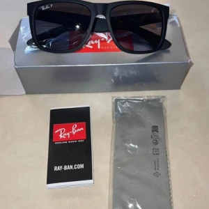 Svarta solglasögon från Ray-Ban - Snygga svarta solglasögon från Ray-Ban med breda skalmar och mörka glas. Klassisk fyrkantig form och Ray-Ban-logga på linsen. Kommer med originalfodral, putsduk och förpackning.