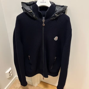 Mörkblå stickad jacka med huva från Moncler - Säljer en mörkblå stickad cardigan från moncler, några defekter och därför ett billigt pris. Kom privat för mer info. 