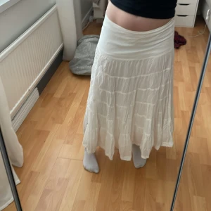 Vit långkjol från Vila - Säljer en vit långkjol från Vila med volangdetaljer. Kjolen har en bred midjeresår och är tillverkad i ett lätt och luftigt bomullsmaterial. Perfekt för en avslappnad och somrig stil.