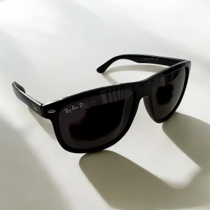 Svarta solglasögon Ray-Ban Wayfarer - Klassiska svarta Ray-Ban boyfreind.Bågarna är i blank svart plast med mörka linser och diskret Ray-Ban-logga på sidan. 