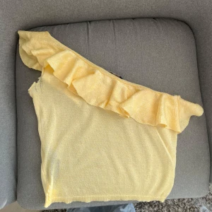 Gul oneshoulder topp med volang från Mango - Snygg gul oneshoulder topp från Mango med glittrigt tyg. Använd några få gånger, storlek S🫶🏼