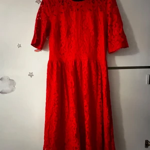 Röd spetsklänning från Holly & Whyte - Säljer en röd spetsklänning från Holly & Whyte med halvärmar och rund halsringning. Klänningen har dragkedja bak och är helfodrad. Perfekt för dig som vill sticka ut med en färgstark look!