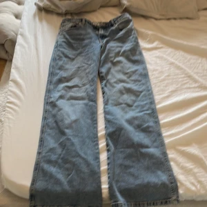 Blåa vida jeansbyxor - Säljer ett par blåa jeansbyxor med breda ben och klassisk femficksdesign. Byxorna har normal passform och är tillverkade i denim. Perfekta för en avslappnad och trendig look.
