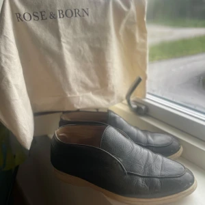 Gröna openwalks från Rose & Born - Stilrena loafers i skinn från Rose & Born. Skorna har en klassisk design med rund tå och ljus sula, perfekt för dig som gillar en clean och tidlös look. Mjukt läder både utvändigt och invändigt för extra komfort. Lite slitna inuti men annars fint skick, vid fler frågor eller funderingar hör av dig!