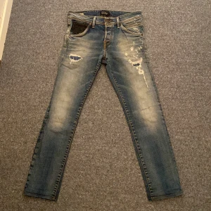 Slim fit jeans Glenn Jack & Jones - Säljer ett par blå slim fit jeans Glenn med slitna detaljer och lätt tvättad look. Byxorna har klassisk femficksdesign och smal passform. Perfekta för dig som gillar en modern och avslappnad stil. byxorna sitter som 29/32 men storleken är 30/32 jag tycker det inte stämmer dem är i nyskick.    Hör av dig vid minsta fundering