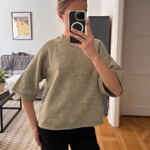 Grön stickad tröja med vida ärmar - Säljer en grön stickad tröja med rund hals och trekvartsärmar. Tröjan har en rak och lite boxig passform, perfekt för lager på lager. Enkel och stilren design som passar till mycket.