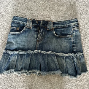 Jeanskjol med volang från Lipp Denimwear - Supersnygg kort jeanskjol från Lipp Denimwear med volang och råa kanter nertill. Klassisk blå denim med slitningar, femficksmodell och volang. 