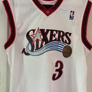 Philadelphia 76ers baskettröja Iverson #3 - Klassisk vit baskettröja från Philadelphia 76ers med nummer 3 och Iverson på ryggen. Andvänd en gång! Köptes i Stockholm ny pris 1 200kr. Lite smuts på ryggen men går att tvätta. Pris inte hugget i sten