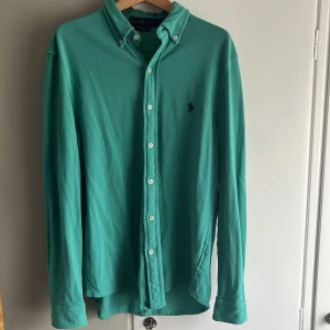 Turkos långärmad skjorta från Ralph Lauren - Säljer en turkos långärmad skjorta från Ralph Lauren i modellen Featherweight Mesh. Skjortan har klassisk krage med knappar och broderad logga på bröstet. Tillverkad i 100% bomull för en skön och luftig känsla.