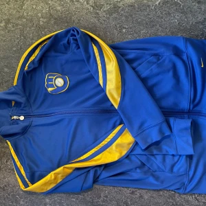 Milwaukee Brewers Nike Ziptröja – Äkta MLB Vintage - 📸 Strl: L (unisex fit – sitter snyggt oversized på M också) 🧢 Äkta Nike x MLB ziptröja med klassisk Milwaukee Brewers-logga 🔵💛 Kungsblå med gula detaljer – sjukt snygg färgkombo 🇺🇸 Direkt från USA – svår att få tag på i Sverige! 🔥 Perfekt till festival, streetwear eller vintage outfits  💡 Retrovibe deluxe – ziptröja som garanterat sticker ut i sommar. Grym kvalitet, luftig mesh, sitter skönt som lager på lager-plagg. 💯 Original “Genuine MLB Merchandise” – se tag på bild!
