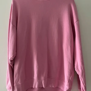 Oversized rosa sweatshirt - En oversized sweatshirt i en snygg rosa färg. Tröjan har rund halsringning, långa ärmar och ribbade muddar vid ärmslut och nederkant. Perfekt för en chill och avslappnad stil. Har en liten fläck (se bild)