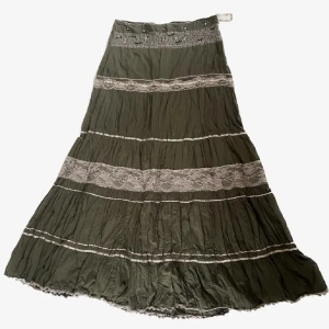 Hippie långkjol Vero Moda - Säljer en olivgrön långkjol med flera breda spetsband i vitt och dekorativa sömmar. Kjolen har en bohemisk känsla