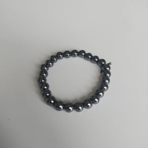 Svart pärlarmband med glans - Stilrent armband med svarta, glansiga pärlor trädda på elastisk tråd. Perfekt accessoar för att ge din outfit en cool och minimalistisk touch. Passar både ensam eller i kombination med andra armband.