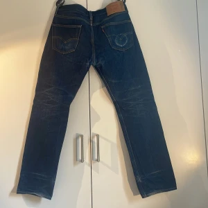 Levi's 501 blå jeans W31 L32 - Klassiska blå Levi's 501 jeans med raka ben och femficksdesign. Tydliga kontrastsömmar och ikonisk läderpatch bak i midjan. Jeansen har normal passform och är tillverkade i slitstarkt denimtyg mad bra fades het en liten fläck på baksidan men inget märkbart