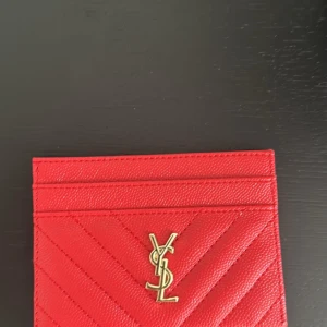 Elegant röd korthållare i skinn – stilren design - Säljer en elegant och stilren korthållare i rött skinn. Väldigt sparsamt använd och i mycket fint skick. Smidig storlek som rymmer det viktigaste – perfekt för dig som vill kombinera stil och funktion i vardagen.  Mjukt skinn Klassisk modell med diskret logga framtill Röd färg med fina detaljer Inga skador, endast mindre spår av normalt brukOriginalförpackning och kvitto saknas, därav det förmånliga priset.  Skickas välpackad med spårbar frakt. Frågor? Hör gärna av dig innan bud!