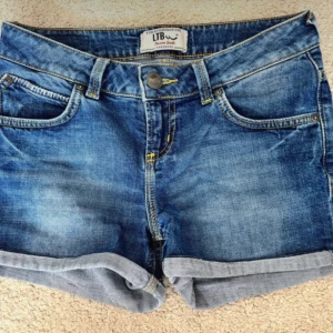 Blå jeansshorts från LTB, XS - Snygga blå jeansshorts från LTB i klassisk femficksmodell med uppvikta benslut och kontrastsömmar. Shortsen har normal passform och lowwaist. Skulle säga att den passar som både XS och S. 