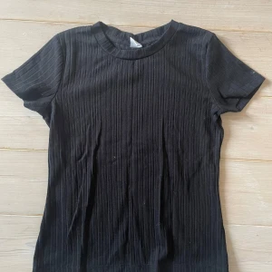 Svart ribbad topp från Lindex - En svart ribbad topp från Lindex med korta ärmar💕 Köpt för länge sedan men ändå knappt använd