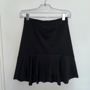 Svart volangkjol - En söt svart volangkjol från BIKBOK som är sydd i ett mjukt, slätt tyg. Kjolen är i storlek M men passar även S. Perfekt för mysiga sommarkvällar! 🖤