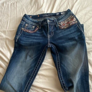 Vintage miss me jeans - Snygga blå skinny jeans från Miss Me med broderade och dekorerade fickor både fram och bak. Jeansen har tydliga kontrastsömmar och midwaist passform. Perfekta för dig som vill ha något unikt och detaljerat i garderoben. Pris kan diskuteras.