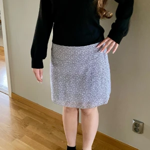 Vit och svart prickig kjol H&M - Kort kjol från H&M i vitt med svarta prickar. Kjolen har rak passform och är tillverkad i ett lätt, mjukt tyg som känns skönt mot huden. Perfekt för dig som gillar en enkel men ändå trendig look.