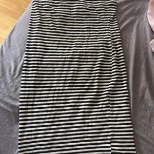 Svartvit randig långkjol - Säljer en svartvit långkjol med smala horisontella ränder. Kjolen har en rak passform och är gjord i ett mjukt och stretchigt material, perfekt för en avslappnad och stilren look.