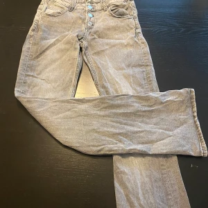 Grå jeans från Gina Tricot, stl 152 - Snygga grå bootcut jeans från Gina Tricot i storlek 152. Säljer då de är för små för mig. De har flera knappar och är väldigt sköna att ha på sig🤩