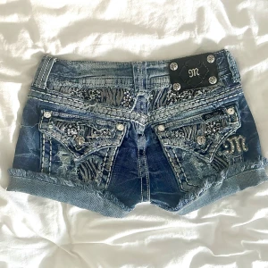 Miss Me jeansshorts med paljetter, strl 26 - Snygga blå jeansshorts från Miss Me med zebramönstrade detaljer, paljetter och slitningar. Shortsen har låg midja, fransig kant och dekorativa bakfickor med bling och broderier. Perfekta för dig som vill sticka ut i sommar! Storlek: 26, Midjemått: ca 34.5 cm. Hör av dig gärna vid frågor!💓