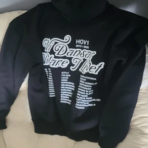 BYTES! Svart Hov1 hoodie med turnétryck strl S - Svart hoodie från Hov1 med stor vit turnétext 'Vi Dansar vidare I Livet' och turnéorter på ryggen. Framsidan har en liten broderad Hov1 krona. Klassisk huva och känguruficka. Jag köpte den i Luleå testat en gång men den var för liten för mig och därför om det är någon som har den i strl M så vill jag gärna byta. Eller att någon som ska på någon av deras nästa konserter som vill ha den i strl S köper den i strl M och sen byter med mig, vad som helst går bra jag vill bara jättegärna ha den i M!😊💕 