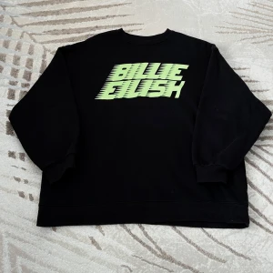 Svart Billie Eilish sweatshirt - Svart tröja med neongrönt tryck "BILLIE EILISH" på framsidan. Officiell merch från H&M-kollektionen. Oversized modell i storlek S – passar även M beroende på önskad passform.  Material: 60% bomull, 40% polyester – mjuk, varm och perfekt för höst/vinter.  Använt skick, få fläckar (se bilderna för detaljer), inget som dock stör helhetsintrycket.