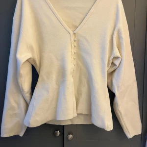 Krämvit kofta med knappar Gina Tricot - Superfin krämvit kofta från Gina Tricot med v-ringning och dekorativa knappar framtill. Koftan har lång ärm, perfekt att slänga på sig över ett linne eller t-shirt. Mjuk och skön känsla i materialet. ANVÄND EN GÅNG. Föreslå gärna ett pris 