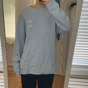 Ljusblå Studio Archive sweatshirt - Ljusblå sweatshirt från Studio Archive med vit text på bröstet. Tröjan har en relaxed passform, rund halsringning och långa ärmar med breda muddar. Tillverkad i mjuk bomull, perfekt för chill dagar eller när du vill ha en enkel och clean look.