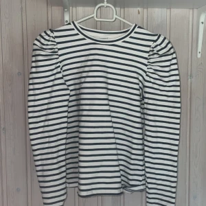 Randig långärmad tröja från Lindex - Säljer en vit och marinblå randig långärmad tröja från Lindex med puffade axlar💞. Tröjan har rund halsringning och är gjord i mjuk bomull🥰säljer för att den är för liten för mig som är 174